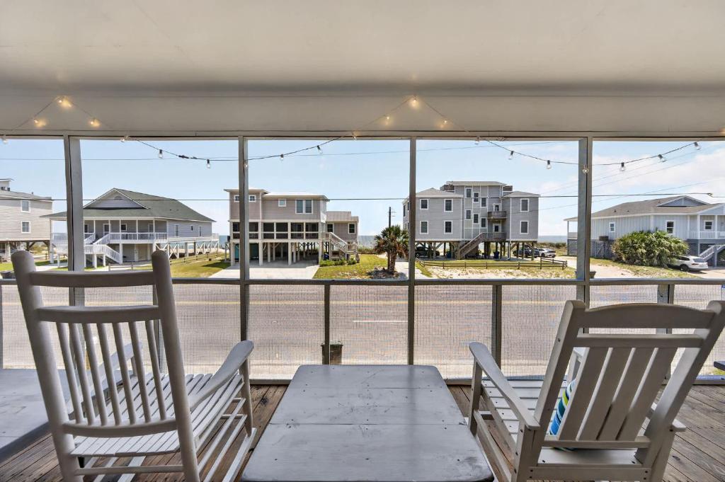 two chairs and a table on a porch with a view of a street at The Edistoneyan in Edisto Island