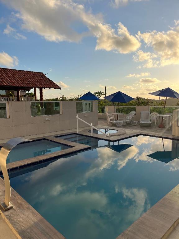 a large swimming pool with chairs and umbrellas at Villa Velha Flats in Itamaracá