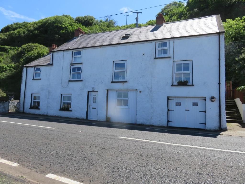 a white house on the side of a road at The Coach House Self Catering Apartments in Glenariff