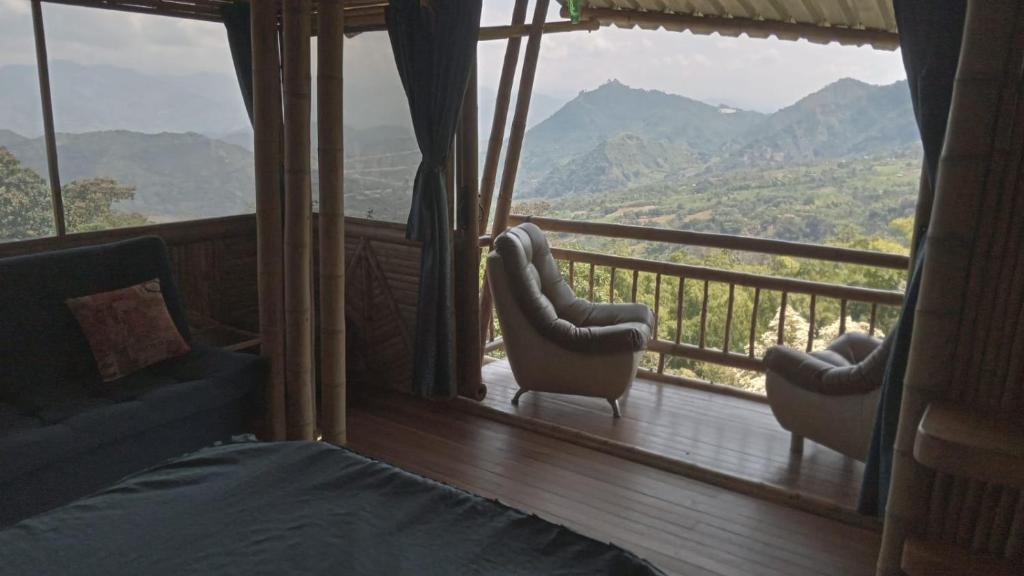 a bedroom with a balcony with a view of mountains at Cabañas la pradera in Ruiosucio