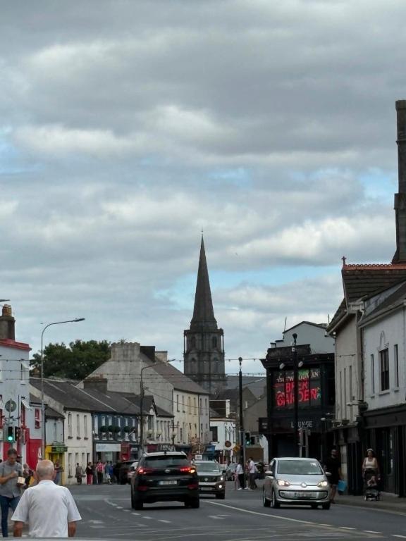 a town with cars driving down a street with a church at The City Walls Residence in Waterford