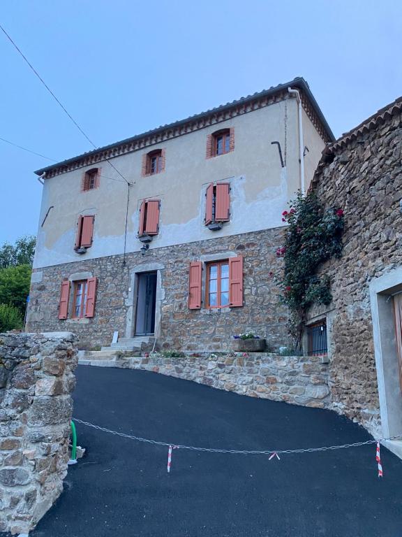 a large stone building with red shutters on it at Chez Phil et Marie in Pralong