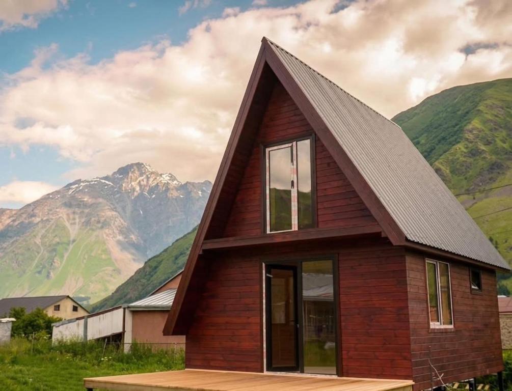 a small house with mountains in the background at Kazbegi mountain station in Kazbegi