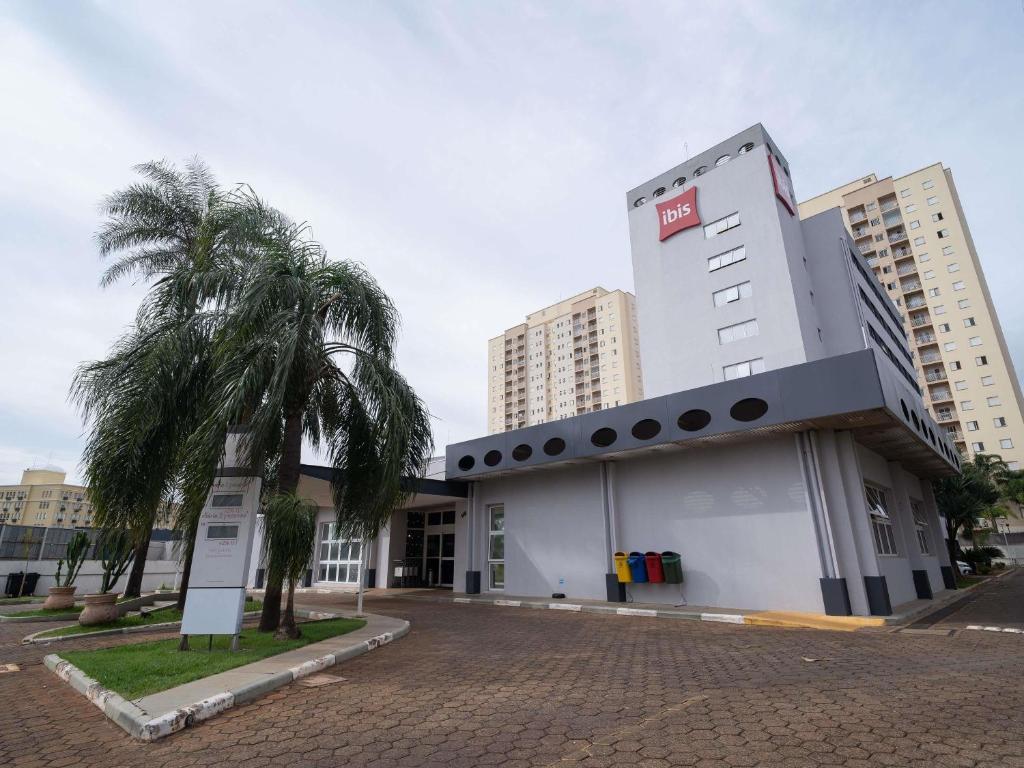 a building with a palm tree in front of it at Ibis São Carlos in São Carlos
