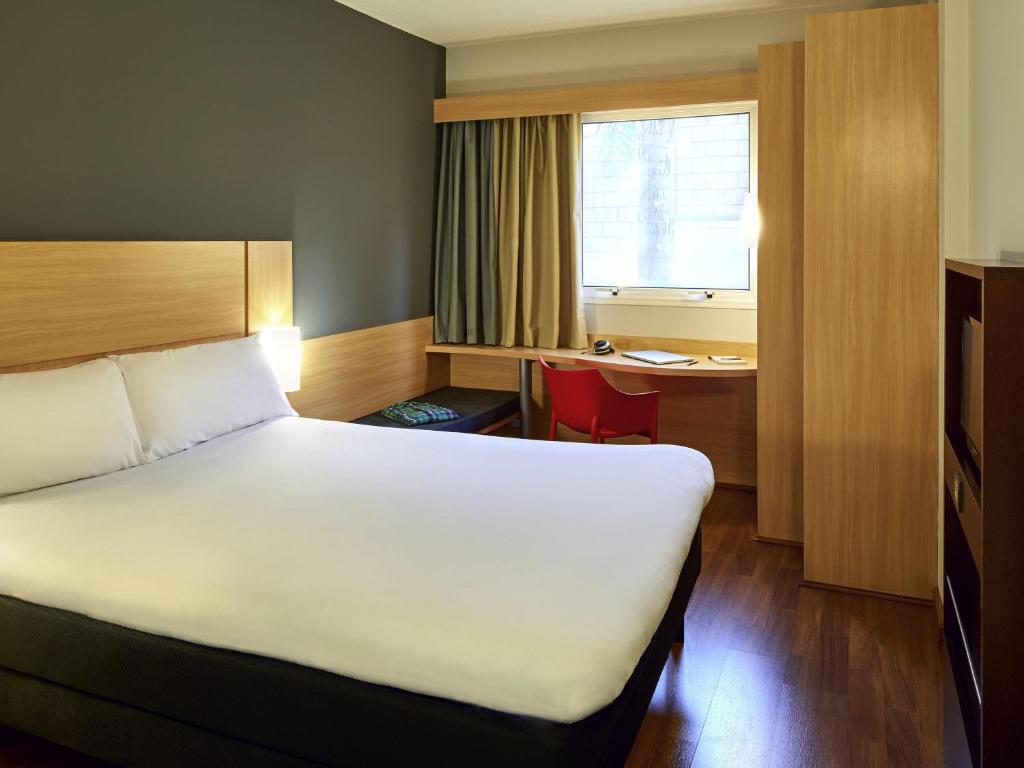 a hotel room with a bed and a desk and a window at ibis Sao Jose do Rio Preto in Sao Jose do Rio Preto