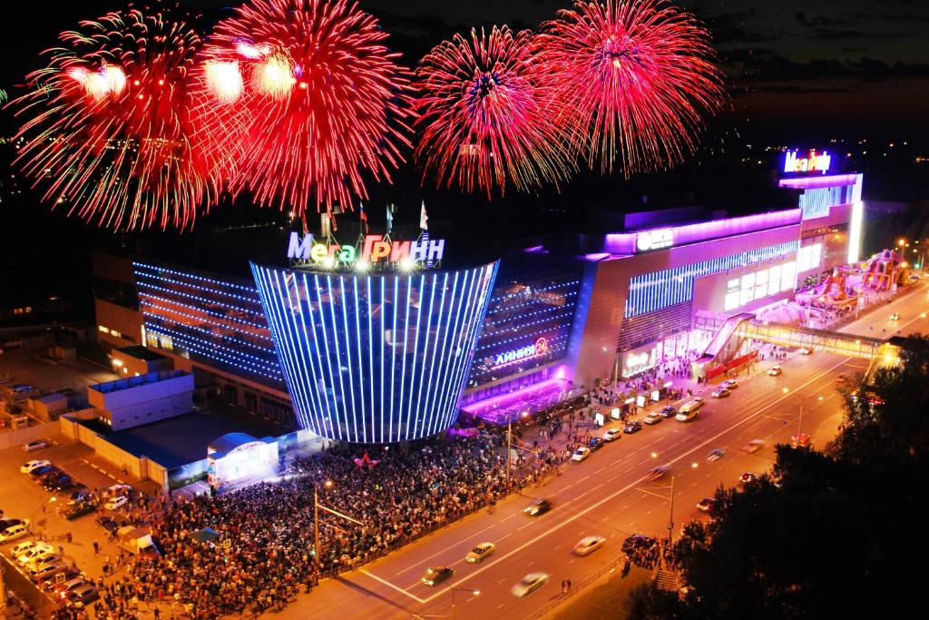 a crowd of people watching fireworks explode over a city at Gostinitsa Grinn in Kursk