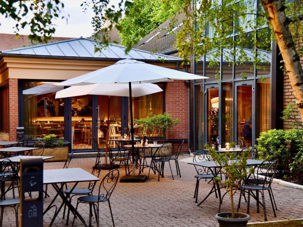 an outdoor patio with tables and chairs and an umbrella at ibis Maisons Laffitte in Maisons-Laffitte
