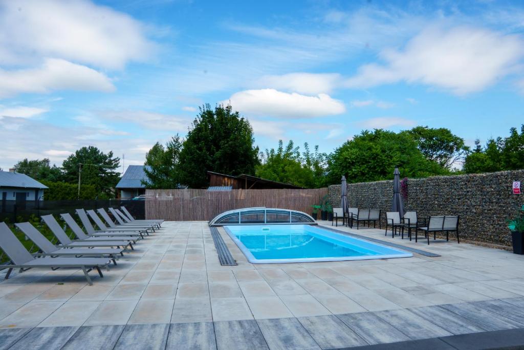 a swimming pool with lounge chairs next to a brick wall at Domki SHERWOOD in Gawłowo