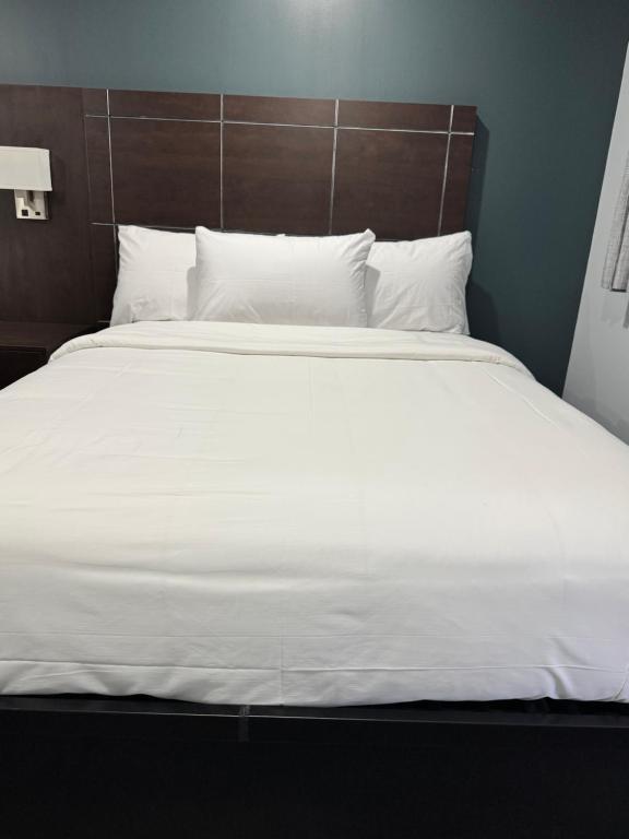 a large white bed with white sheets and pillows at Countryside Inn in Kingston