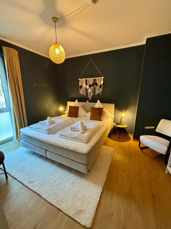 a bedroom with a large bed and a chandelier at Klinik & Kurpark Parkplatz Barrierefreies Apartment Boxspringbett in Bad Oeynhausen