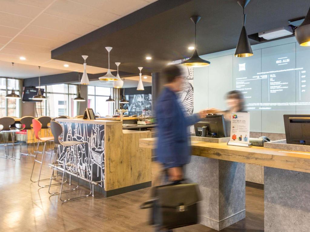 a person walking past a counter in a restaurant at Ibis Albi in Albi