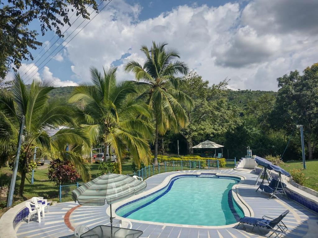a swimming pool with palm trees in the background at Finca Hotel Campestre Salitre Villeta in Villeta