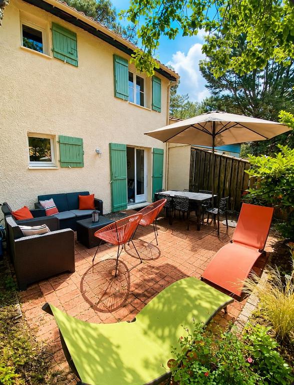 a patio with a table and chairs and an umbrella at Agréable maison rénovée in Lacanau-Océan