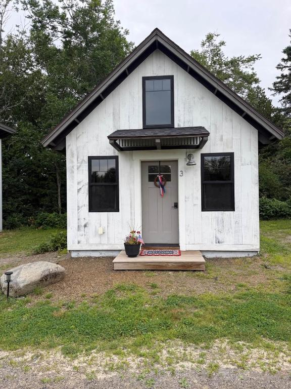a white house with a door and a porch at The Evergreen | Walk to Rangeley Lake, Sled & ATV Access in Rangeley