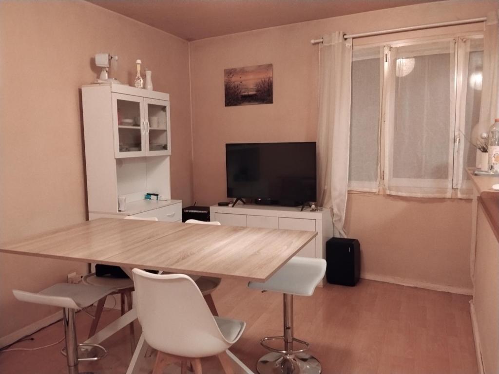 a dining room with a wooden table and white chairs at Le rdv incontournable in Nancy