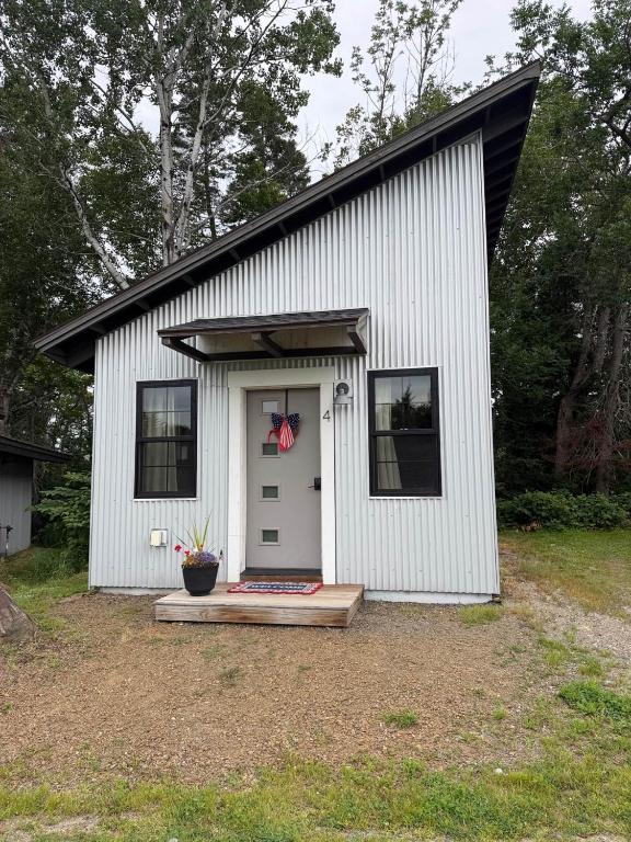 a small white shed with a white door and windows at The Ridgeline | Near Saddleback • Walk to Rangeley Lake in Rangeley