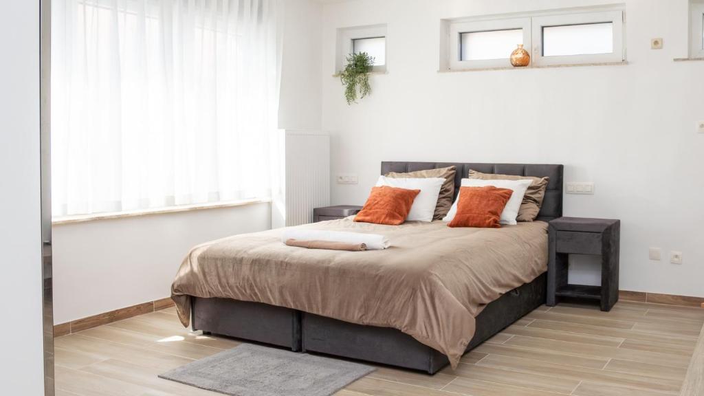 a bedroom with a large bed with orange pillows at Alvastay - Cozy studio in Haaltert