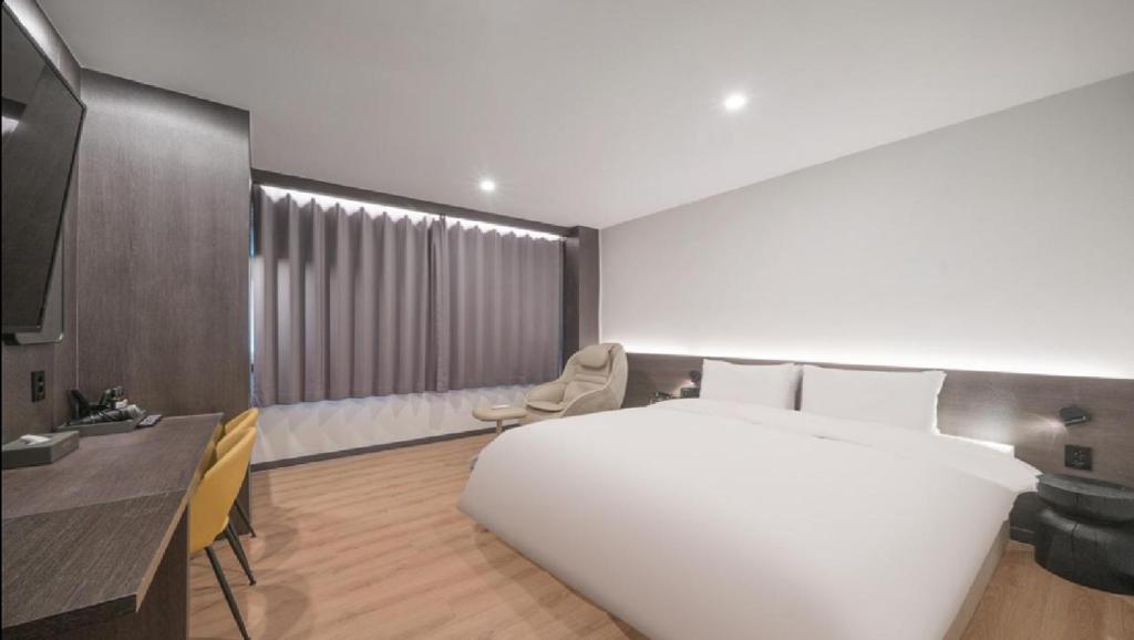 a bedroom with a large white bed and a desk at HOTEL lantana in Tudomi