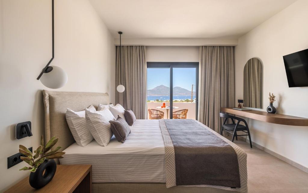 a bedroom with a bed with a desk and a balcony at Serenya Hotel Milos in Adamantas