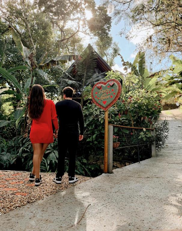 a man and a woman standing next to a heart sign at Cabana com Cachoeira Privativa in Imaruí