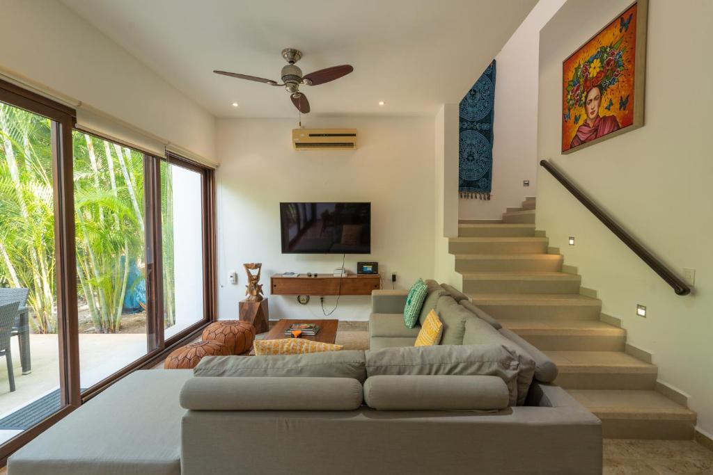 a living room with a couch and a staircase at Townhome with private Rooftop & Jacuzzi - Beach across street in Akumal