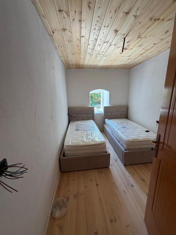two beds in a room with a wooden ceiling at Kulla e Xhem Gjokes 