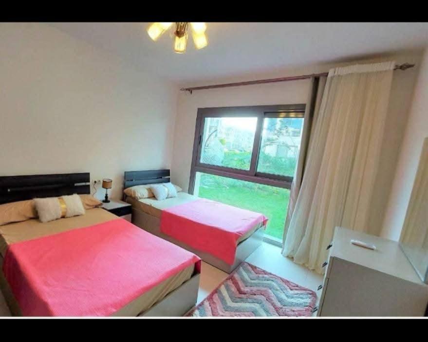 a room with two beds and a window with at Chalet Marina 2 Marassi in El Alamein