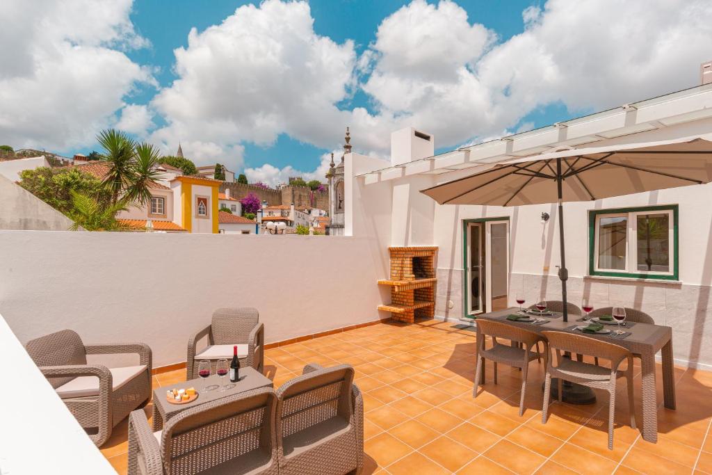 a patio with tables and chairs and an umbrella at Retiro do Livro in Óbidos