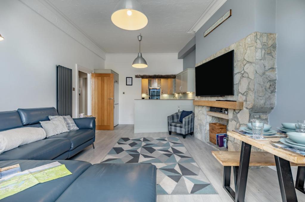 a living room with a blue couch and a tv at Ocean view in Swanage