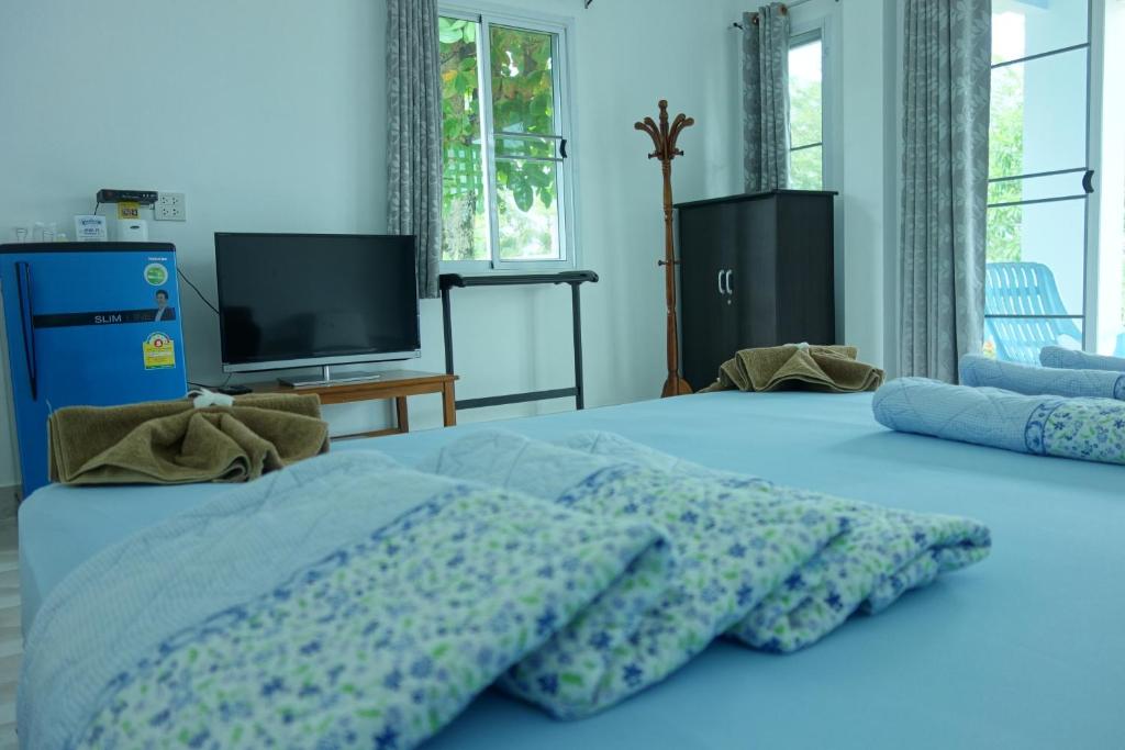 a bedroom with a blue bed with pillows and a tv at Mook Ing Lay in Ko Mook