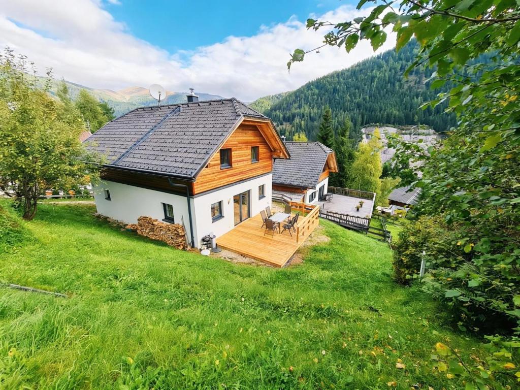 a large wooden house with a deck in a field at Sauna Chalet Ahorn in Bad Kleinkirchheim