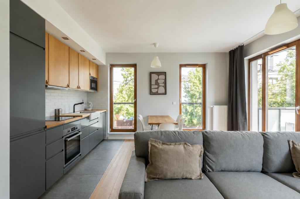 a kitchen and living room with a gray couch at Warsaw Concierge Gocławek in Warsaw