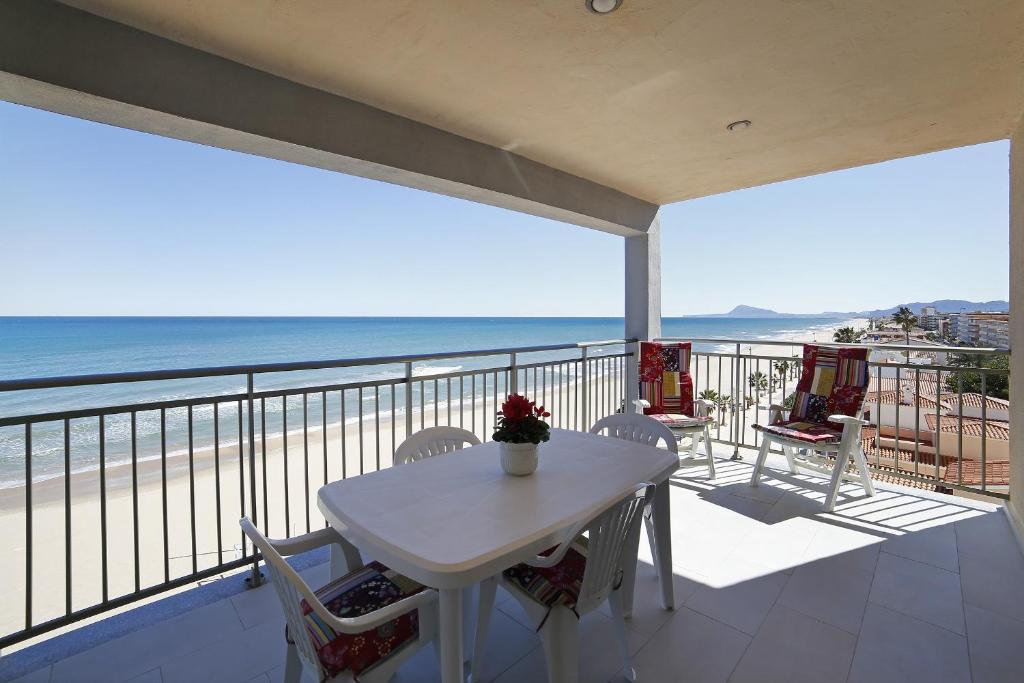 una mesa blanca y sillas en un balcón con vistas a la playa en Apartamento frente al mar, en Bellreguart