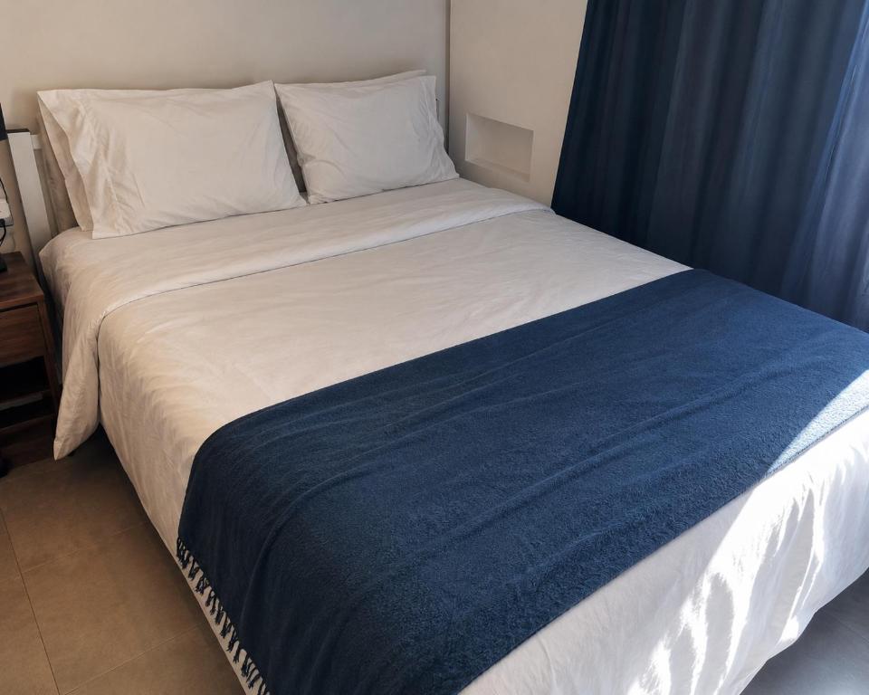 a bed with a blue and white blanket on it at Studiohaus Alvorada in São Paulo