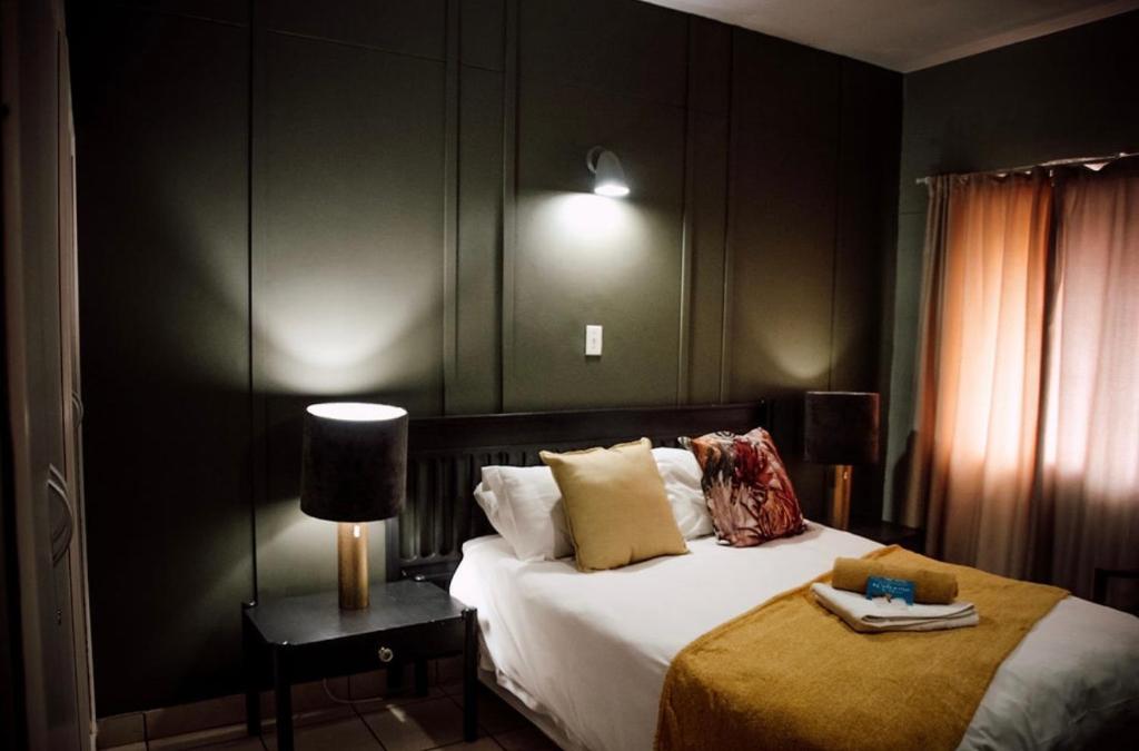 a bedroom with a bed and a lamp on a table at Postmasburg hotel in Postmasburg