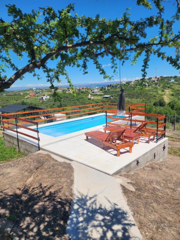 a pool with tables and benches next to a tree at Cabañas Dulce Atardecer in Villa Carlos Paz