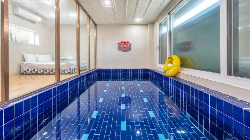 a swimming pool in a room with blue tiles at Gapyeong Ddel Poolvilla in Gapyeong