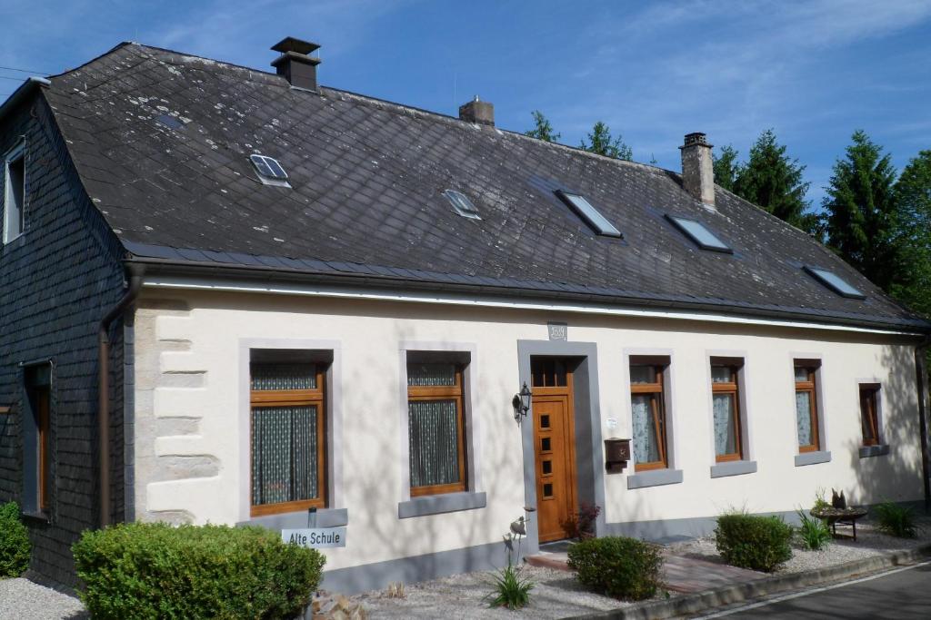 ein altes weißes Haus mit schwarzem Dach in der Unterkunft Ferienwohnungen Alte Schule in Elchweiler