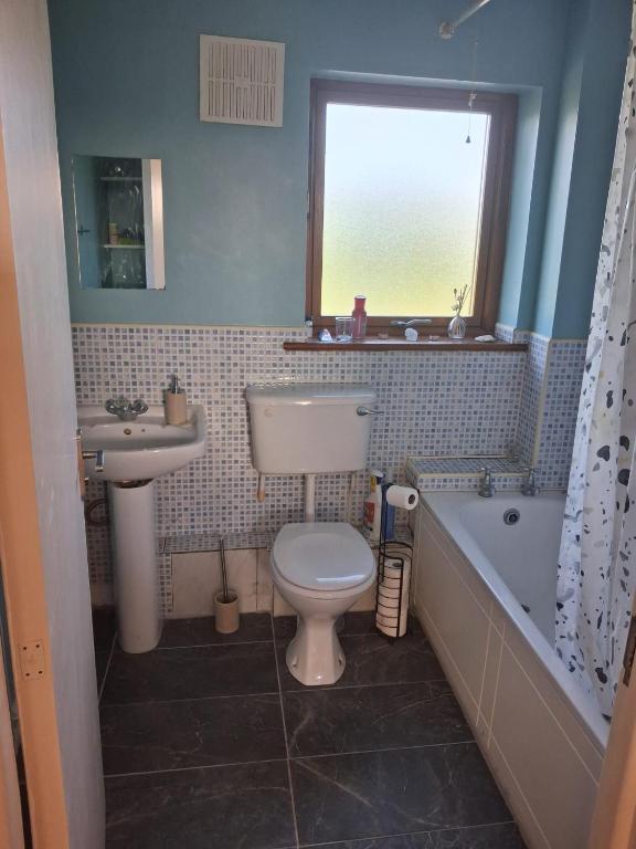 a bathroom with a toilet and a sink and a tub at 2 bedroom house 