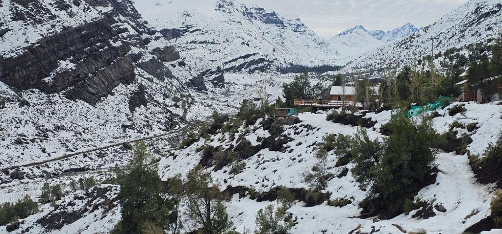 a snow covered mountain with a small town in the foreground at Cabaña Valle del Yeso in El Manzanito