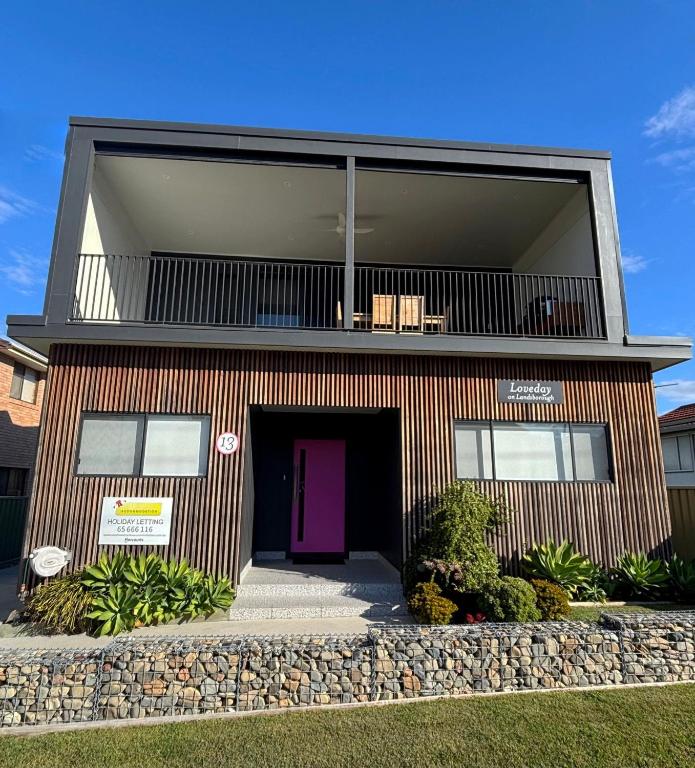 a house with a purple door and a stone wall at Loveday on Landsborough in South West Rocks