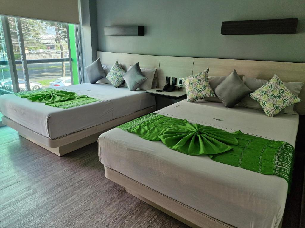 due letti in una camera d'albergo con lenzuola verdi di HOTEL LEMON GREEN -Zona Expo Frente al Centro de Convenciones a Guadalajara