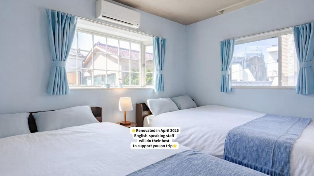 a bedroom with two beds and two windows at 75m2 10people private house rental 8beds 8min Ikebukuro 13min Shinjuku 18min Shibuya Englishspeaking staff available in Tokyo