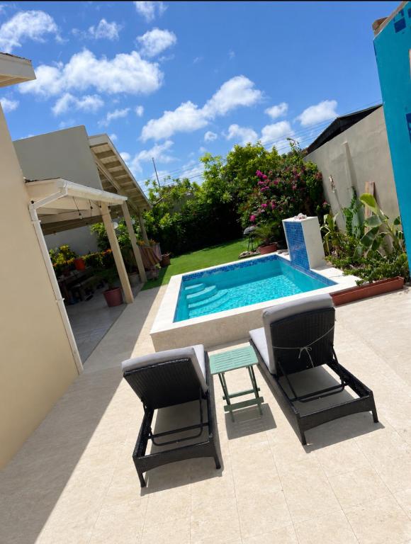 a swimming pool with two chairs and a table next to a pool at La Villas at Pos Chiquito Caribbean Paradise in Aruba in Savaneta