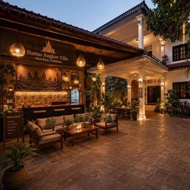 a patio with couches and tables in front of a building at NAMO ANGKOR VILLa in Siem Reap