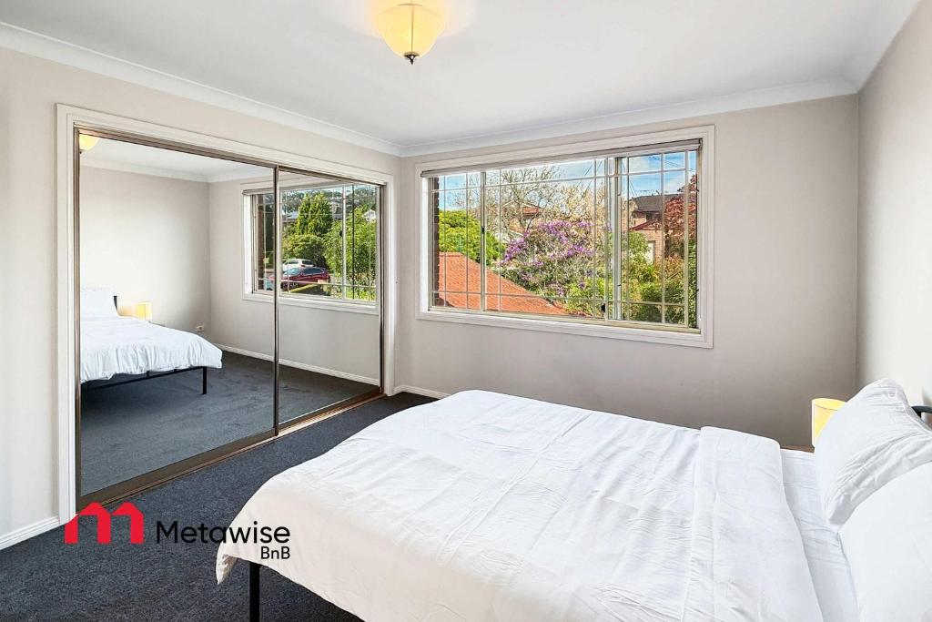 a bedroom with a white bed and a window at Spacious 4-Bedroom Home in Cherrybrook in Cherrybrook