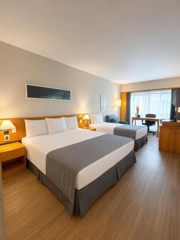 a hotel room with two beds and a desk at Sol Alphaville Hotel By Your Alpha Stay 1602 in Barueri