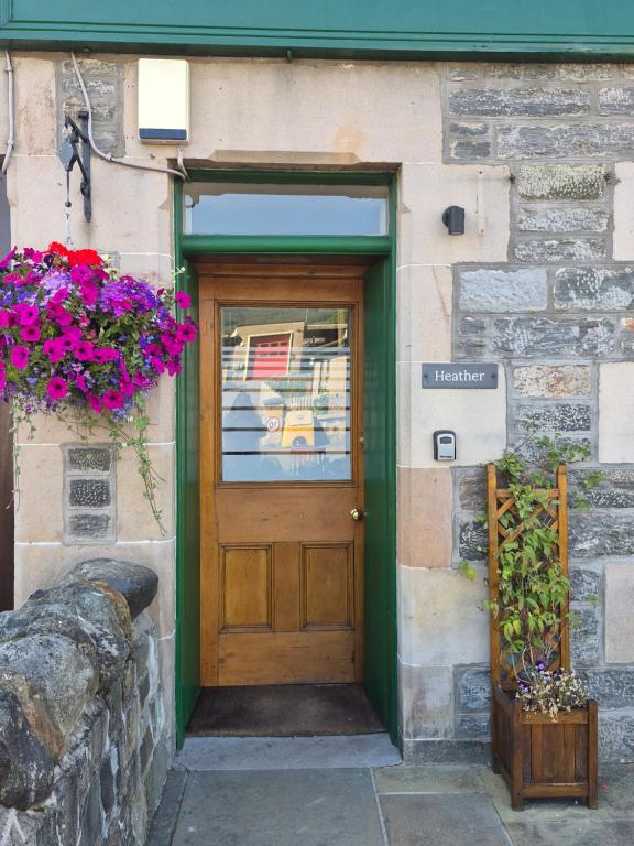 a wooden door on a building with flowers on it at CRAIGLEA HEATHER in Killin