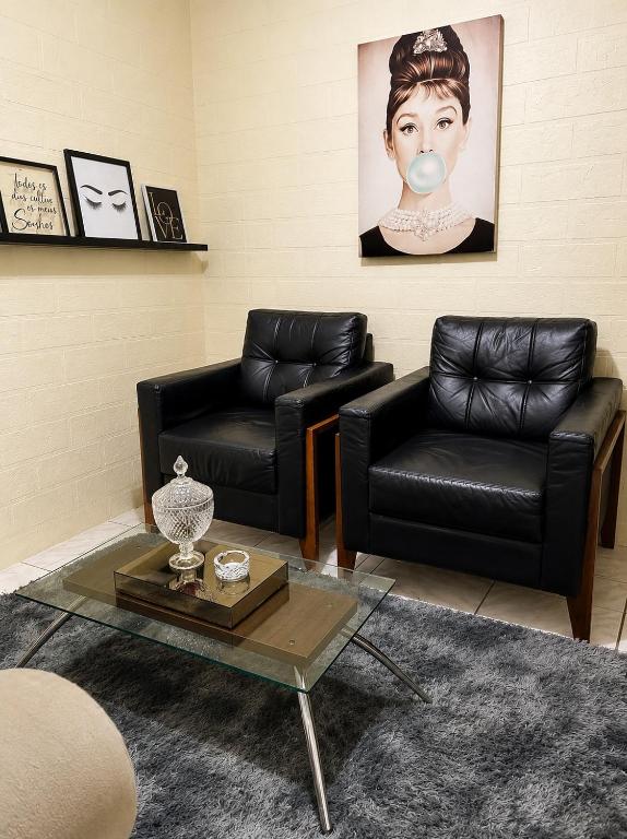 a living room with two leather chairs and a table at Aconchego in Fortaleza