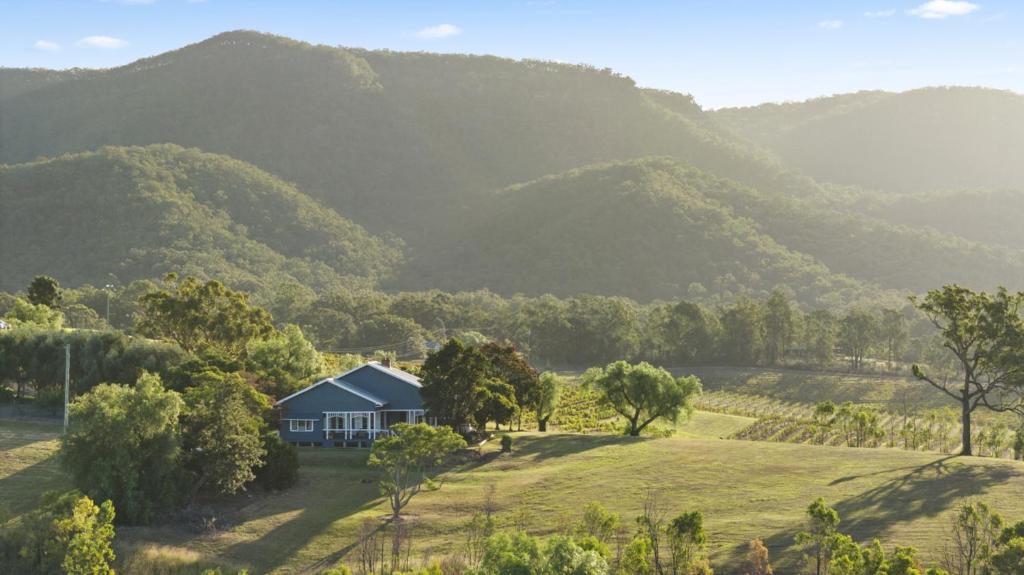 a house in a field with mountains in the background at Audrey Wilkinson Vineyard in Pokolbin